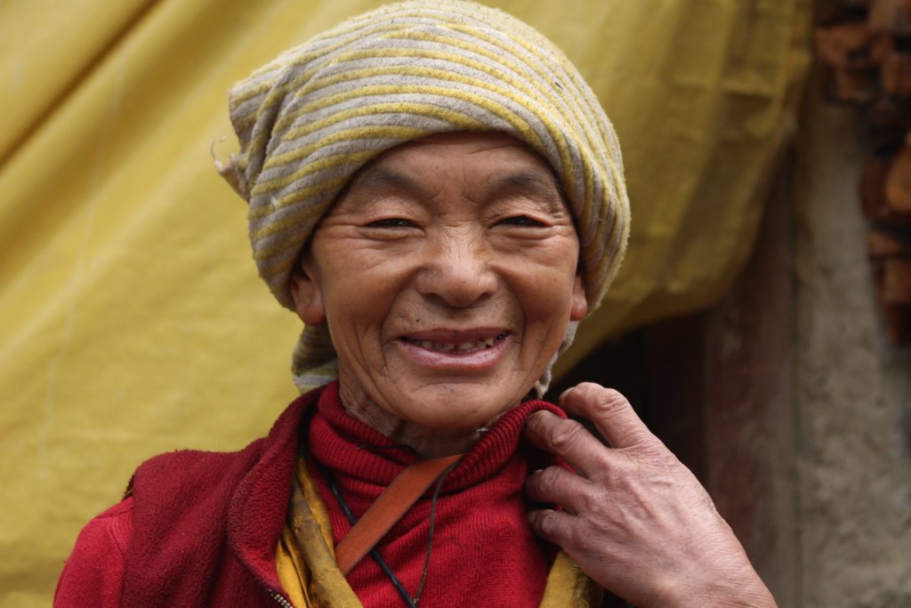 An elderly nun tending to a Gompa in the valley